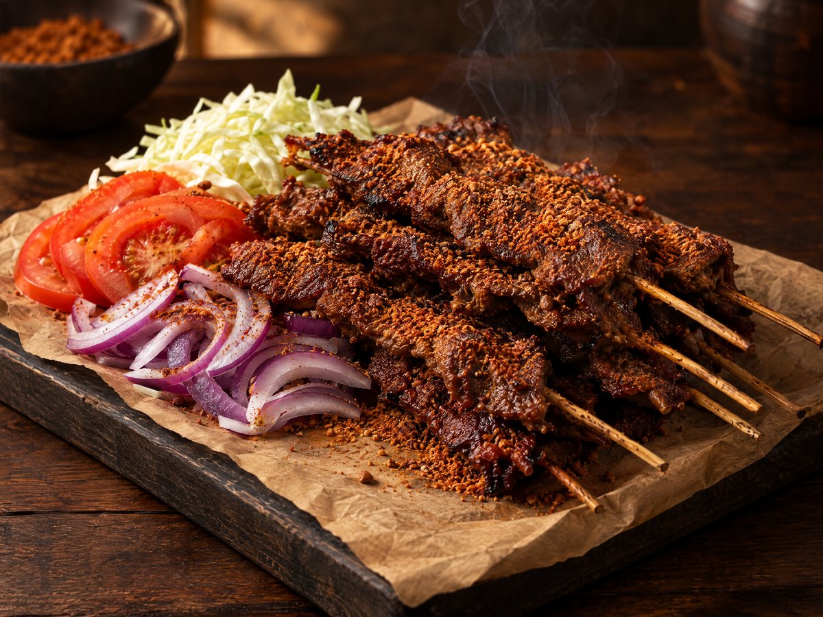 Suya beef skewers with raw onion and tomato