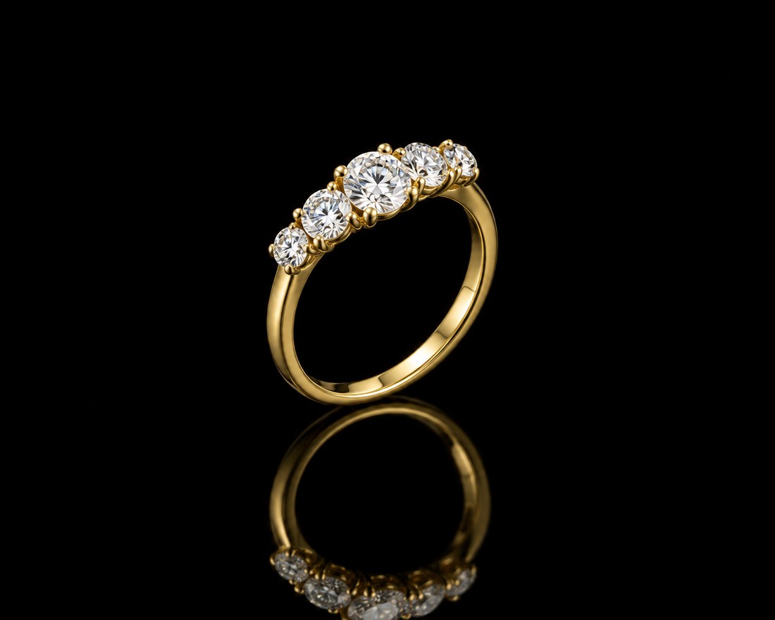 Five graduated round diamonds in a row on a yellow gold anniversary band