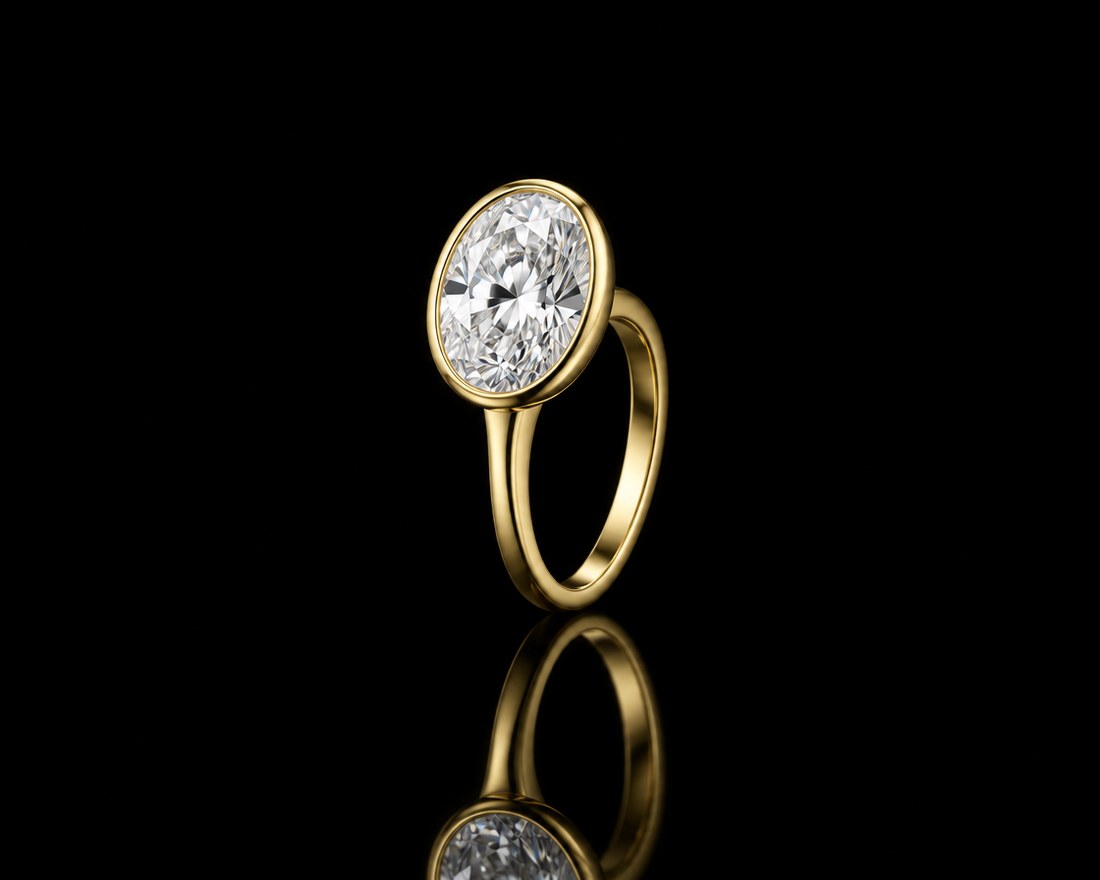 Oval diamond in a polished yellow gold bezel on a slim band