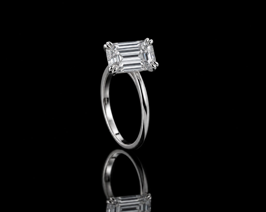 East-west emerald-cut diamond solitaire on a slim platinum band