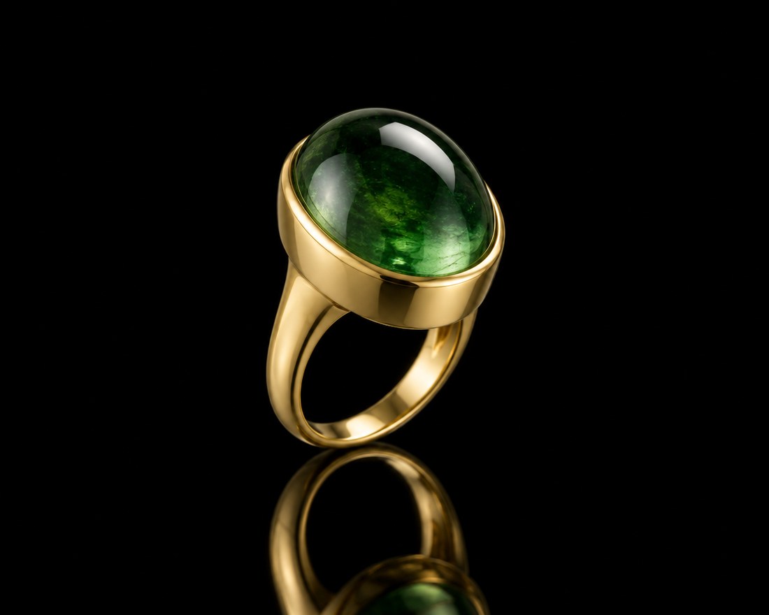 Domed green tourmaline cabochon in a yellow gold bezel ring