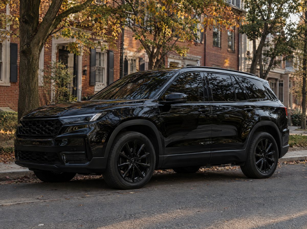 Black SUV with very dark window tint and blacked-out trim parked on a brick-lined street in autumn